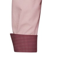 Polsino di camicia a maniche lunghe in tessuto rosa chiaro con piccoli motivi geometrici; polsino interno testurizzato di contrasto in borgogna scuro.