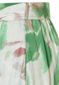 Jupe en tissu à motifs floraux dans des tons de vert et de rose, présentant des plis et une texture lisse. La ceinture est plate avec un léger éclat.