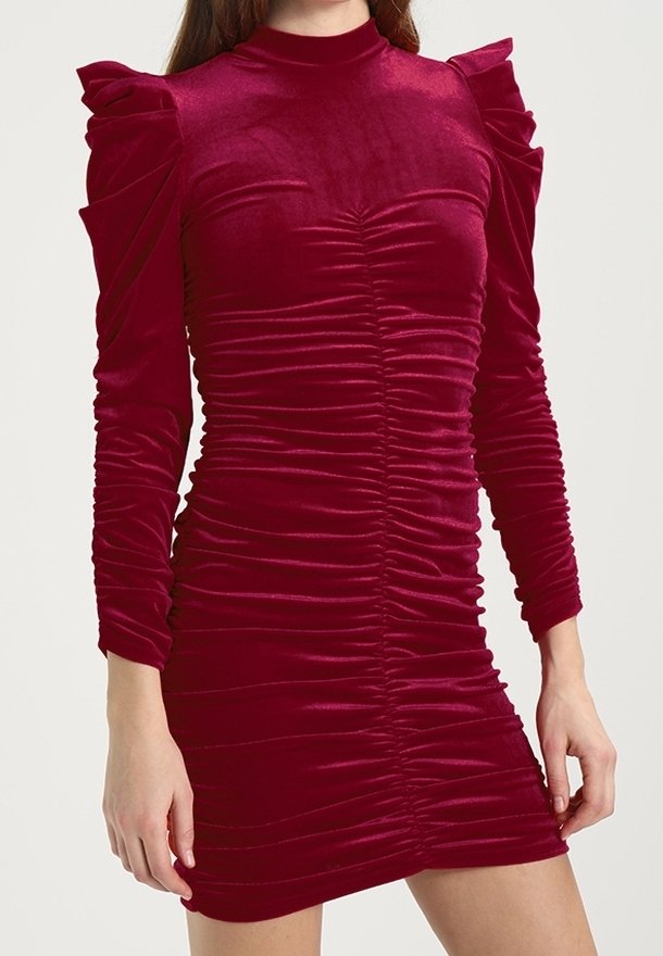 Robe mini en velours rouge ajustée à manches longues, col montant, détails froncés et épaules bouffantes structurées.