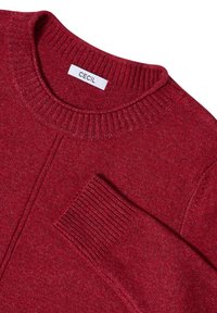 Maglione rosso a maglia con colletto a girocollo e polsini a coste, caratterizzato da una finitura texturizzata e un piccolo etichetta sulla scollatura con la scritta "CECIL".