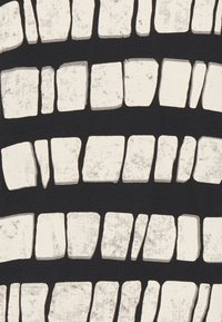 Textil que presenta bloques rectangulares blancos irregulares sobre un fondo negro. Los bloques varían en tamaño y textura, con un aspecto ligeramente desgastado.