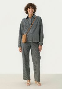 Gestreepte set met een shirt en broek in donkergrey en wit. Van katoen met een ontspannen pasvorm. Inclusief een bruine crossbody tas. Lichte platte sandalen.