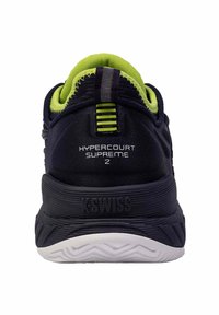 Zapatilla deportiva negra con parte superior de malla y acentos en verde neón. Cuenta con una suela texturizada y la marca "K-Swiss" en el talón.