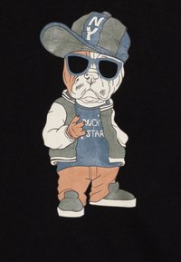 Un bulldog animato che indossa occhiali da sole, un cappellino grigio e blu, una maglietta blu con scritto "ROCK STAR", un gilet grigio e pantaloni arancioni con sneaker grigie.