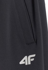 Tissu noir avec une couture verticale et une ouverture de poche avant, arborant un logo blanc "4F" près du coin inférieur droit.