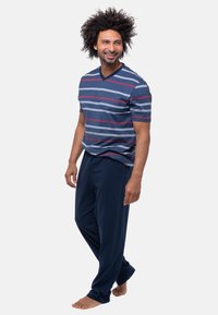 Kortærmet, V-hals stribet skjorte i blå, grå og maroon. Sammen med mørkeblå, løstsiddende bukser. Blød, afslappet loungewear design.