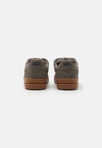 Hallide hall suede kingad pruunist kummist tallast, millel on pehmendatud kaelus ja "VANS" logo kandadel. Madalate spordijalatsite disain.