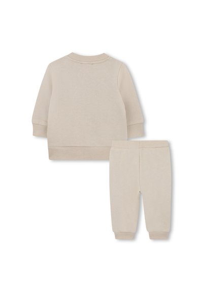 Ensemble de survêtement pour tout-petit en coton beige, avec un haut à manches longues et un pantalon assorti. Poignets et taille côtelés, texture douce et design simple.