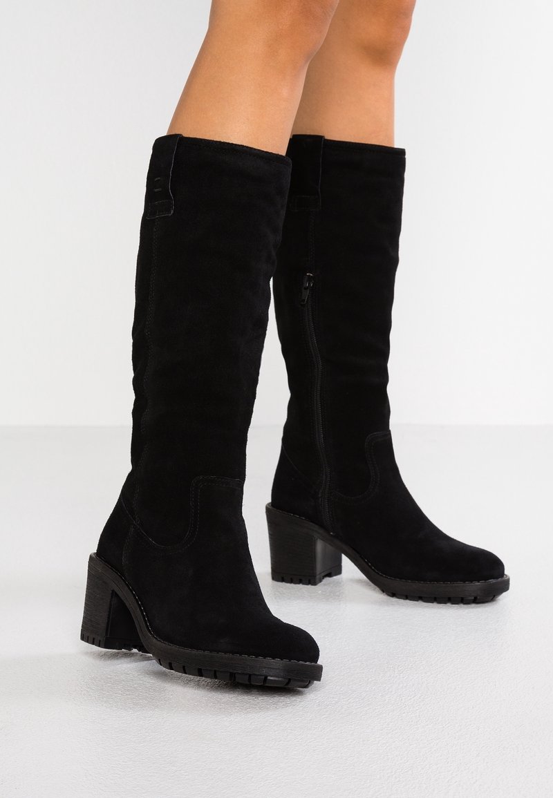 Bottes montantes en daim noir avec talon épais, fermeture éclair latérale et semelle texturée ; détails de couture subtils.