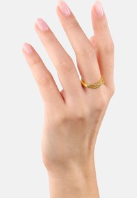 Anillo de tono dorado con diseño entrelazado, exhibido en una mano. Acabado metálico suave y forma redonda, destacando la textura de la banda.