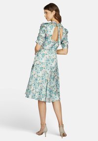 Blumenmusterkleid in Hellblau mit rosa und grünen Mustern. Hat Puffärmel, einen Schlüssellochausschnitt im Rücken und einen fließenden Rock; weicher Stoff.