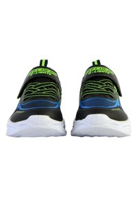 Scarpe da ginnastica nere e blu con dettagli verdi, caratterizzate da un design elegante, fissate con una fascia in velcro e suole in gomma testurizzata.