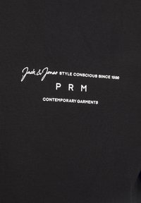 Camiseta de algodón negra con texto impreso en blanco: "Jack & Jones ESTILO CONSCIENTE DESDE 1990" y "PRM PRENDAS CONTEMPORÁNEAS."
