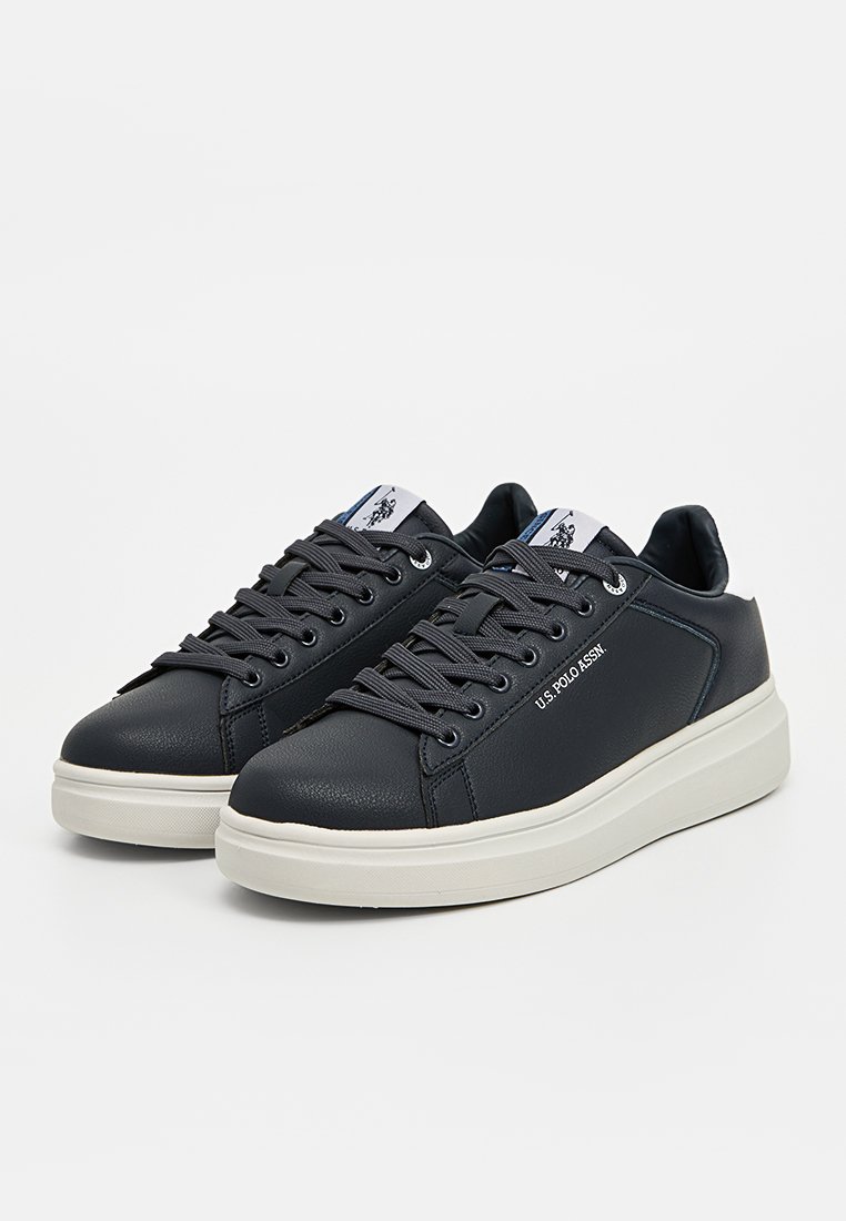 Baskets bleu marine en simili cuir, avec une semelle en caoutchouc blanche, un design à lacets et un logo sur le côté. Ajustement confortable.