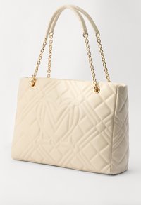 Borsa trapuntata color crema con finitura in pelle liscia, dotata di manici in catena dorata e motivo geometrico.