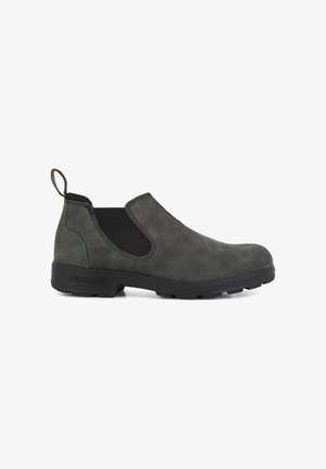 Botines de ante gris oscuro, tipo slip-on, que cuentan con paneles laterales elásticos y una suela de goma negra texturizada, además de una pestaña en el loop para facilitar su uso.