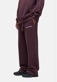 Donker bordeauxrode sweatpants met een relaxte pasvorm, gemaakt van zachte stof. Beschikt over een elastische tailleband, trekkoord en witte logotekst op de bovenbeen.