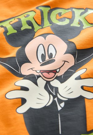 Maglietta arancione con un personaggio dei cartoni animati raffigurato con un mantello nero, guanti bianchi e un'espressione giocosa su uno sfondo arancione.