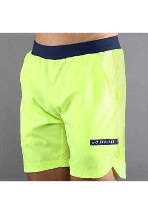 Pantalones cortos deportivos amarillos brillantes con una cintura azul marino y el logo "ENDLESS" en la pierna izquierda, usados por una persona sobre un fondo gris.