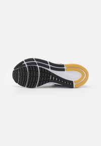 Suola di sneaker Nike caratterizzata da un motivo di battistrada in gomma nera con accenti bianchi e gialli, progettata per trazione e durata.