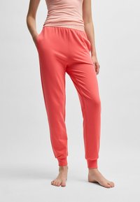 Koraal joggingsbroeken met elastische tailleband, zijzakken en manchethemden. Gemaakt van zachte stof, ideaal voor comfort en casual draagstijl.
