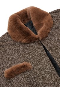 Cappotto marrone a fantasia con un morbido colletto in pelliccia sintetica marrone e dettagli nelle tasche. Tessuto testurizzato con un design intrecciato, caratterizzato da una fodera interna scura.