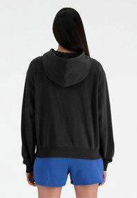 Felpa nera con tasca a marsupio e cappuccio con stringhe, con polsini e orlo a coste, abbinata a pantaloni corti blu. Materiale morbido in misto cotone.