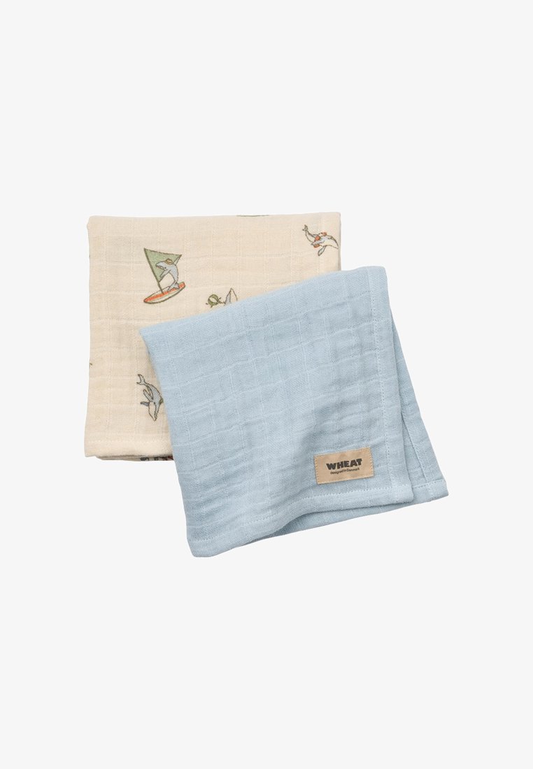 Dwa złożone płótna muślinowe, jedno jasnoniebieskie z etykietą "Wheat", drugie beżowe z małymi, kolorowymi nadrukami zwierząt i żaglówek.