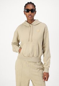 Beige hoodie i mjukt tyg, med en framfickan för känguror, snörning och ribbade ärmslut, tillsammans med matchande sweatpants.