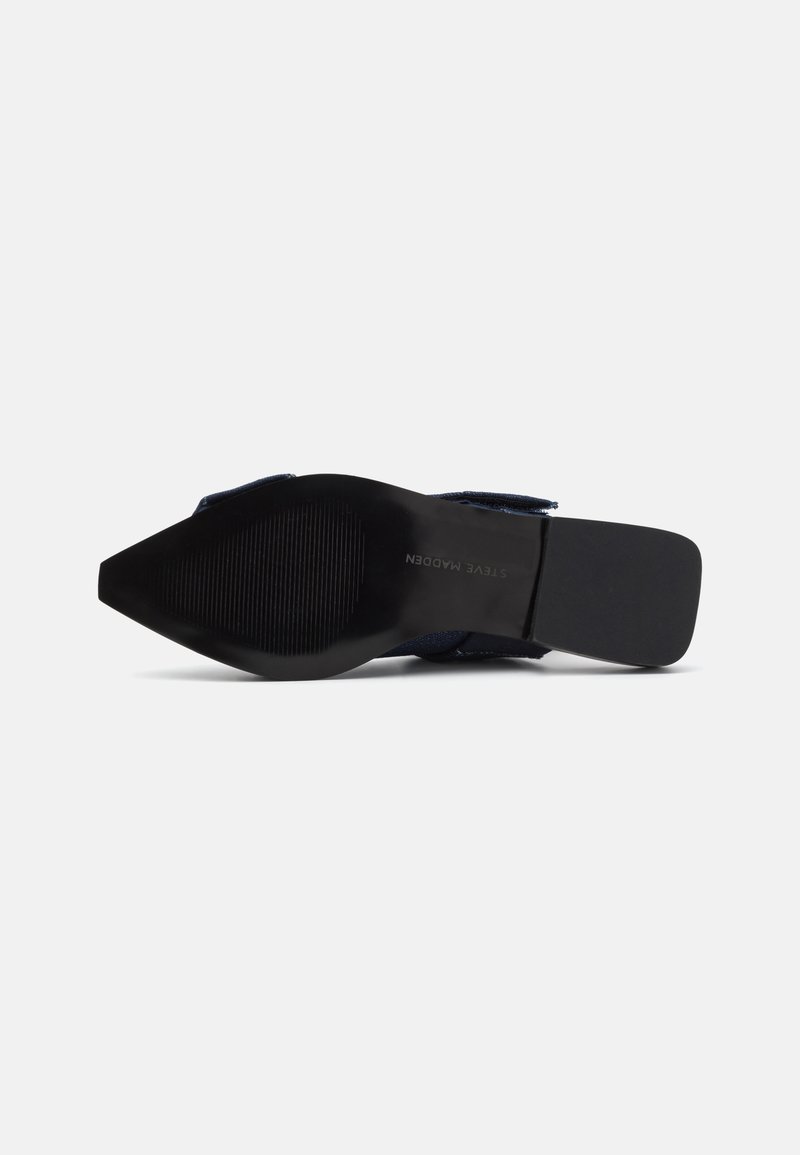 Spitz zulaufende Schuhsohle aus schwarzem Gummi, mit einem strukturierten Grip-Muster und minimaler Markenkennzeichnung. Leicht geschwungene Kante mit einem eleganten Profil.