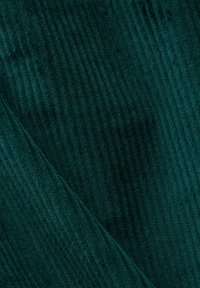 Turkoois fluwelen ribstof met een verticale geribbelde textuur, voorzien van een zachte, duurzame afwerking en een diagonale vouw die een gelaagde uitstraling creëert.