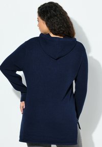 Mörkblå hoodie med lång ärm, ribbat mönster på ärmarna och en avslappnad passform. Har en ventilation på baksidan.