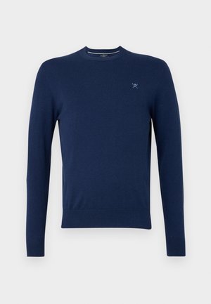 Mornarsko plava pulover s okruglim izrezom, izrađen od soft tkanine, s dugim rukavima i malim, svijetloplavim logom na lijevoj strani prsiju. Glatka tekstura.