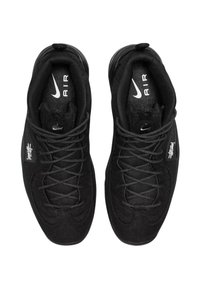 Une paire de baskets Nike Air noires avec des lacets noirs et un logo blanc sur les semelles intérieures, vues de dessus sur un fond blanc.