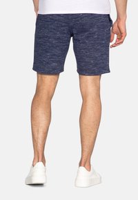 Shorts bleu marine en tissu texturé et chiné. Présentent des poches latérales et une coupe décontractée. Associés à des baskets blanches.