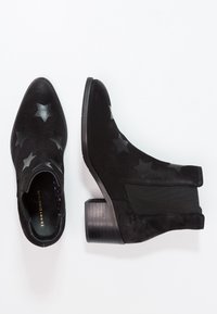 Stivaletti neri in suede con un motivo a stelle, dotati di un lato elastico e di un tacco spesso e texturizzato.
