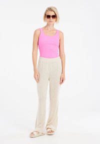 Roze geribde tanktop, crèmekleurige textuur wijde broeken met diamanten patroon, en sandalen met een decoratieve band en dikke zolen.