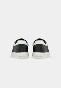Zwarte leren sneakers met een witte, gestructureerde achterkant en zool. Voorzien van een gladde afwerking en een debossed merklogo op de hiel.