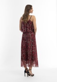 Punainen käärmeennahkakuosis maxi-mekko kerroksellisella selkädesignillä, valmistettu kevyestä kankaasta. Yhdistetty mustiin korkokenkiin.