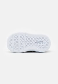Suela de zapatilla blanca con un textura estampada. Presenta una forma redondeada y la marca "adidas" grabada en la superficie.