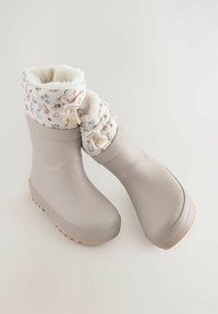 Jasno beżowe, wodoodporne gumowe buty z wzorzystym różowym mankietem, miękkim wyściółką i teksturowaną podeszwą zapewniającą przyczepność. W zestawie regulowany sznurek.