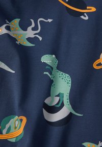 Groene cartoon T-Rex staat op een zwart-wit gestreepte planeet met een pterosaurus en oranje-ringed planeten op een marineblauwe stof achtergrond.