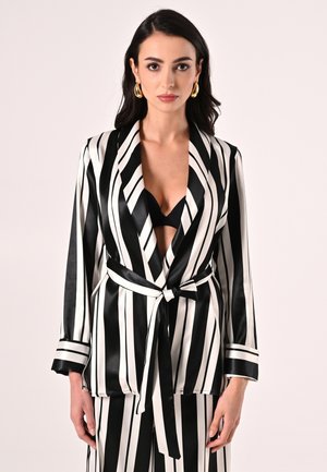 Blazer en satin rayé noir et blanc avec un col en V profond, manches longues, ceinture à la taille et poignets contrastants. Convient aux styles ajustés ou amples.