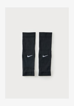 Paar schwarze Nike Kompressionsärmel mit weißen Swoosh-Logos, flach auf einem schlichten hellen Hintergrund abgelegt.