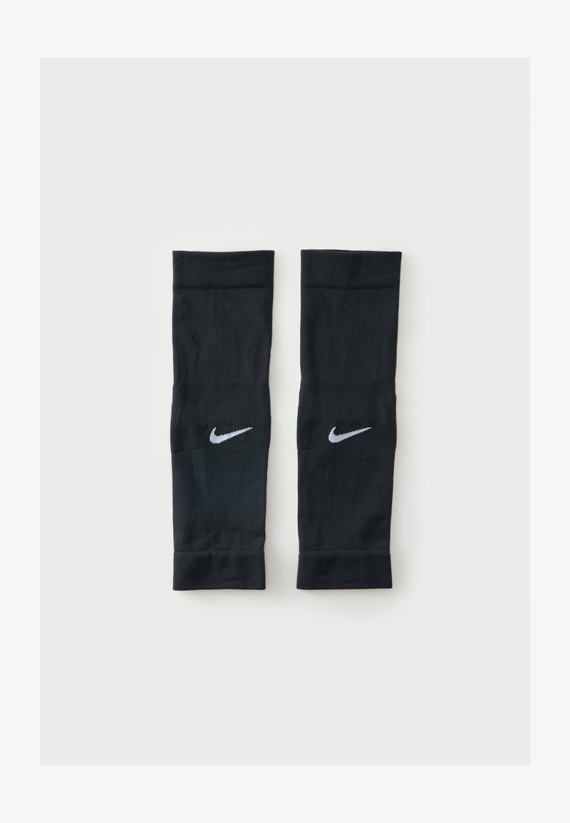 Ζευγάρι μαύρα συμπιεστικά μανίκια Nike με λευκά λογότυπα Swoosh, τοποθετημένα επίπεδα σε απλό φωτεινό φόντο.