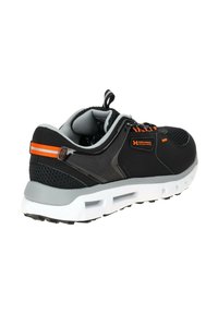 Chaussure de sport noire avec tige en mesh, accents gris et détails orange. Elle possède une épaisse semelle blanche et une texture de grip sur la semelle extérieure.
