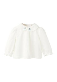 Bela majica z dolgimi rokavi z nazobčanim ovratnikom in svetlo modrimi vezenimi oblikami češenj. Mehka tkanina z nabranimi rokavi pri manšetah.