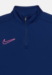 Σπορ μπλούζα ναυτικού μπλε με φερμουάρ έως το στήθος και ροζ λογότυπο Nike στη σχισμή αριστερά στο στήθος.