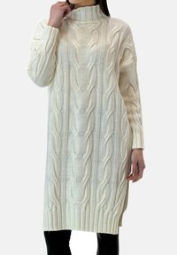 Buksefarvet strikket sweaterkjole med ribkanter ved ærmer og kant, med et kabelstrikket mønster og en høj krave