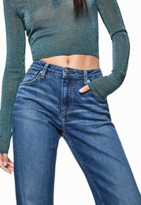 Vaqueros de mezclilla azul con cintura alta, pierna recta y diseño clásico de cinco bolsillos. El material muestra una textura ligera, con detalles de costuras doradas.